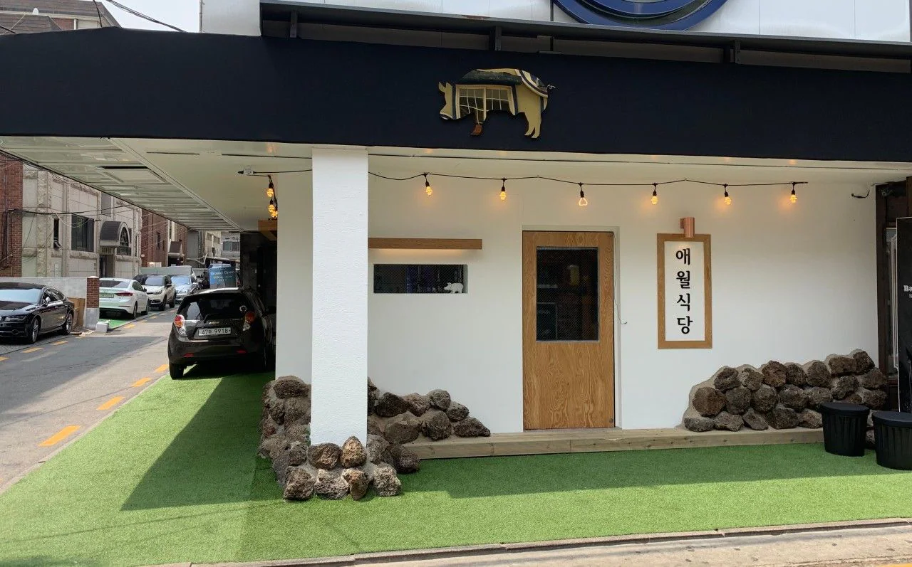 涯月食堂 狎鷗亭店外觀:白牆、黑色遮雨棚與玄武岩石堆