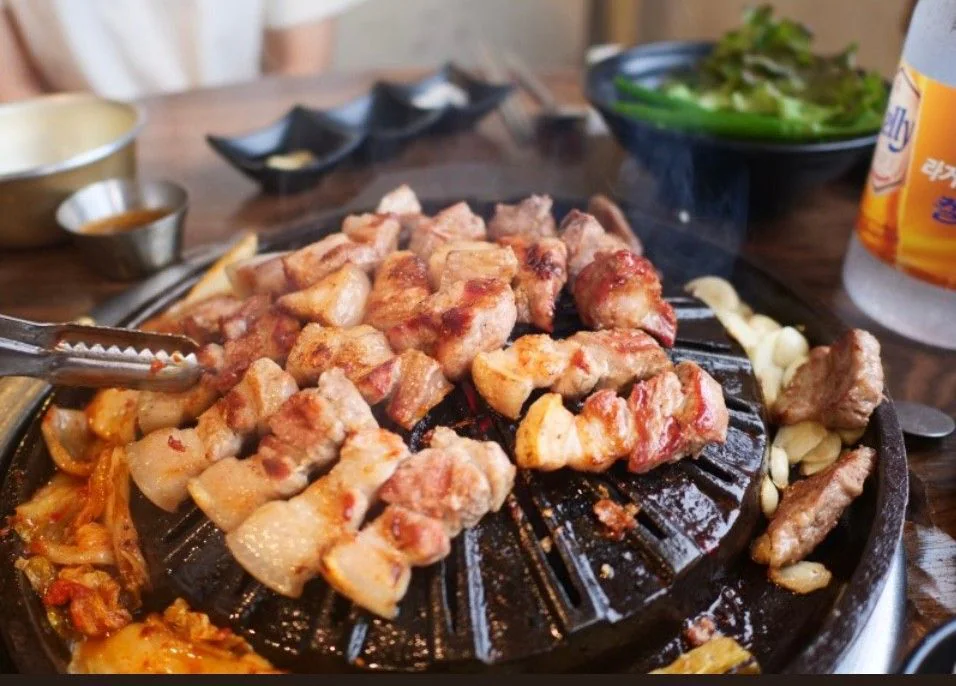 黑色烤盤上烤得金黃的豬肉與泡菜